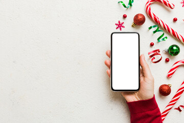 Wall Mural - christmas mockup with space for text. christmas advertising, app template. hand holding phone with empty screen on table background. Happy New Year and Xmas Flat lay