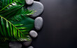 Still life photo of stones, green and palm leaves and candles over black background. Spa and relax concept with copy space. 