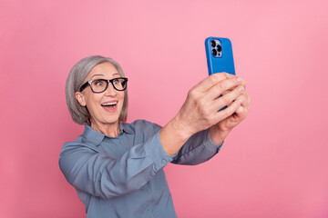 Sticker - Photo of excited crazy cheerful retired lady trendy clothes glasses look camera video meeting live stream isolated on pink color background