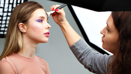 Canvas Print - Backstage of the photo shoot: Make-up artist applies makeup on beautiful white  model. Tutorial makeup master class.