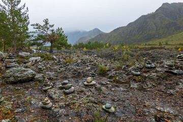 Wall Mural - Pebbles stacked on rocky landscape with scenic mountains in background at Altai, Russia