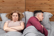 Two in bed, a woman complains, a man turned away in the other direction. Relationship concept