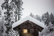 Verschneite Berghütte im Winter mit bleuchtetem Fenster