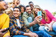 © Davide Angelini - Group of young people using smart mobile phone outdoors - Happy friends with smartphone laughing together watching funny video on social media platform - Tech and modern life style concept