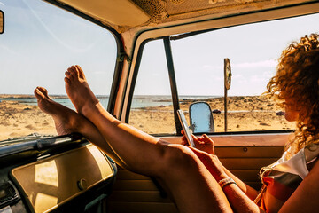 Interior of classic van camper with beautiful legs of woman stretched and relaxed. Travel people lifestyle concept. Summer holiday vacation and vanlife. Dreamcatcher and beach view holiday vacation