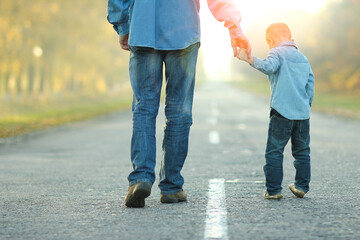 Wall Mural - A Happy parent with child are walking along the road in the park on nature travel