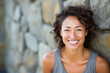 © OPPERMAN - Healthy smiling woman in fitness clothing posing in front of a stone wall.