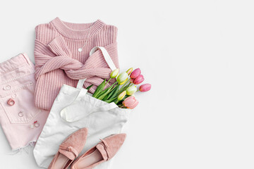 Wall Mural - Fashion spring outfit. Pale pink jumper with bouquet of tulips flowers in bag,  jeans and loafers. Women's stylish and elegant clothes with accessory and jewelry.  Flat lay, top view, overhead.