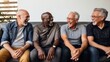 © Stavros - Old male friends of different races laugh remembering times and events sitting on couch in living room of apartment. Positive emotions and lifelong friendship. Laughing at joke with acquaintances