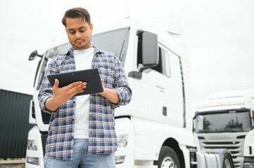 Happy indian courier using tablet in the van . High quality photo