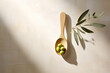 Olives in the small wooden tablespoon with branch of olive tree and soft shadow on white background, flat lay.