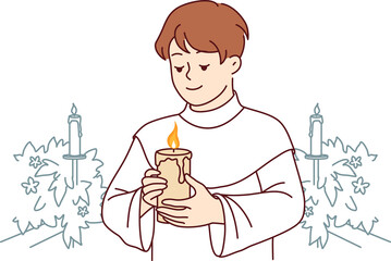 Wall Mural - Boy participates in holy communion and holds burning candle for christian religious ritual in church