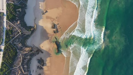 Wall Mural - Drone flying high above the shore with blue waves of amazing beauty and the road and the paths on the shore