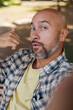 © sutulastock - A bald man with a gray beard takes a selfie, looking into the camera