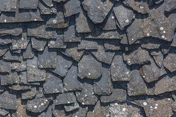 Detailed view of wall texture randomly lined with slate panels, typical and traditional shale stone material, used as external waterproof cladding in construction