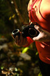 Photographer switch lens outdoor during his Journey in the Woods wearing orange technical shirt
