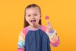 © New Africa - Little girl with lollipop showing tongue on orange background
