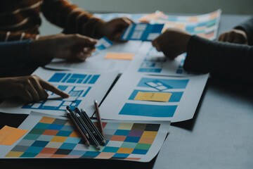 Close up ux developer and ui designer brainstorming about mobile app interface wireframe design on table with customer breif and color code at modern office.Creative digital development agency
