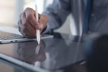 Businessman, manager using stylus pen signing e-document on digital tablet with laptop computer on table at modern office, e-signing, electronic signature, paperless office, digital document concept