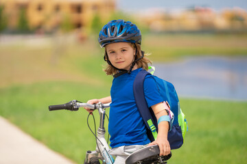 Little kid boy ride a bicycle in the park. Kid cycling on bicycle. Happy smiling child in helmet riding a bike. Boy start to ride a bicycle. Sporty kid bike riding on bikeway. Kids bicycle.