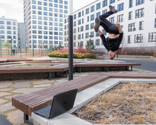 A Man Types On A Laptop Outdoors And Then Does A Somersault. 