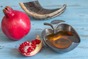 Wall Mural - Fresh honey, pomegranate fruit for Jewish holiday Rosh Hashanah on blue wooden background.