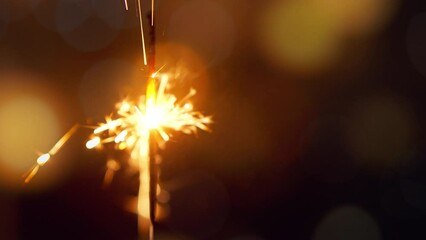 Wall Mural - Closeup of lightening sparkler on gold bokeh background, Bengal lights are burning, Birthday or new year eve night party. Happy holiday celebration.