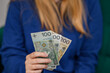 Kobieta trzyma wachlarz polskich banknotów PLN w dłoni
