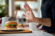 Close-up of male hand showing stop gesture to cheeseburger