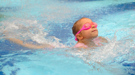 Wall Mural - Child diving in swimming pool. Toddler kid jumping into the water in goggles learning to swim. Girl having fun in water, splashing in aquapark