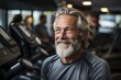 © photolas - A smiling elderly gray-haired man in good athletic shape in the gym against the background of many sports equipment.