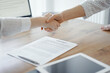 © rogerphoto - Business people shaking hands above contract papers just signed on the wooden table, close up. Lawyers at meeting. Teamwork, partnership, success concept