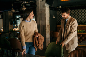 Smiling business people relaxing just walk into a restaurant, take off their jackets, and sit at the table.