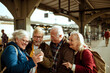 © Davor - Senior people friends looking at mobile phone in train station