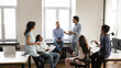 © fizkes - Diverse young business team employee speaking to group of colleagues, sharing ideas on office meeting, talking to group. Corporate teacher, mentor training multiethnic staff. Banner shot
