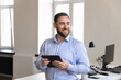 © fizkes - Happy successful millennial businessman holding digital tablet computer, looking away, thinking, planning, smiling , using gadget for wireless Internet connection, online app for job tasks