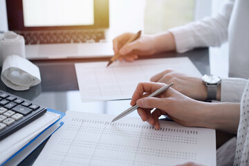 Two accountants use a calculator and tablet computer for counting taxes or revenue balance. Business, audit, and taxes concepts