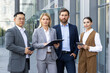 © Liubomir - Portrait of a happy group of businessmen of different genders and nationalities standing on the street near the office, looking seriously at the camera.