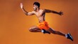 © Marko - Athletic man jumping in dynamic pose, dance, wearing orange shirt and pants, yellow background, studio portrait