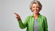 © Favio - mujer anciana feliz apuntando con su dedo, cabello corto y blanco, vestida de verde, aislada en un fondo blanco