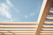 Wooden pergola frame against a blue sky with clouds.