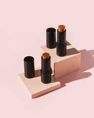 Two cream bronzer sticks on pink pedestals 