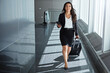 © Grady Reese/peopleimages.com - Walking, airport or happy businesswoman with phone, suitcase or luggage on social media. Travel, booking trip or corporate worker texting to chat on mobile app on international flight transportation