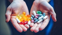 Human hands hold a handful of colorful pills and capsules. Assortment of pharmaceutical drugs, pills in hands