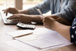 © fizkes - Close up young couple calculating domestic bills, checking financial documents, using laptop, man and woman browsing online banking service, paying taxes, family planning managing budget together