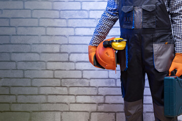 Wall Mural - Builder handyman with construction tools against wall background with copy space.