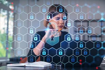 Wall Mural - Pensive attractive beautiful businesswoman in formal wear working on laptop at office workplace in background. Concept of data protection information technology. lock icon hologram.