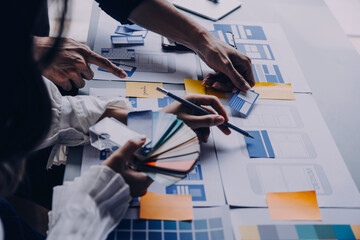 Close up ux developer and ui designer brainstorming about mobile app interface wireframe design on table with customer breif and color code at modern office.Creative digital development agency
