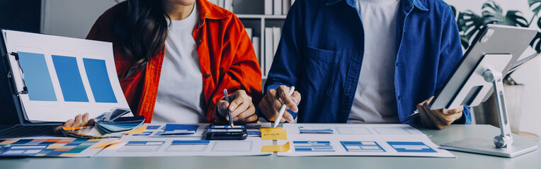 Close up ux developer and ui designer brainstorming about mobile app interface wireframe design on table with customer breif and color code at modern office.Creative digital development agency