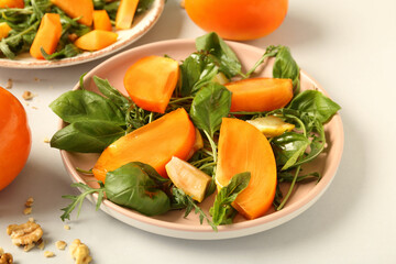 Plate of delicious salad with persimmon and lemon on white background